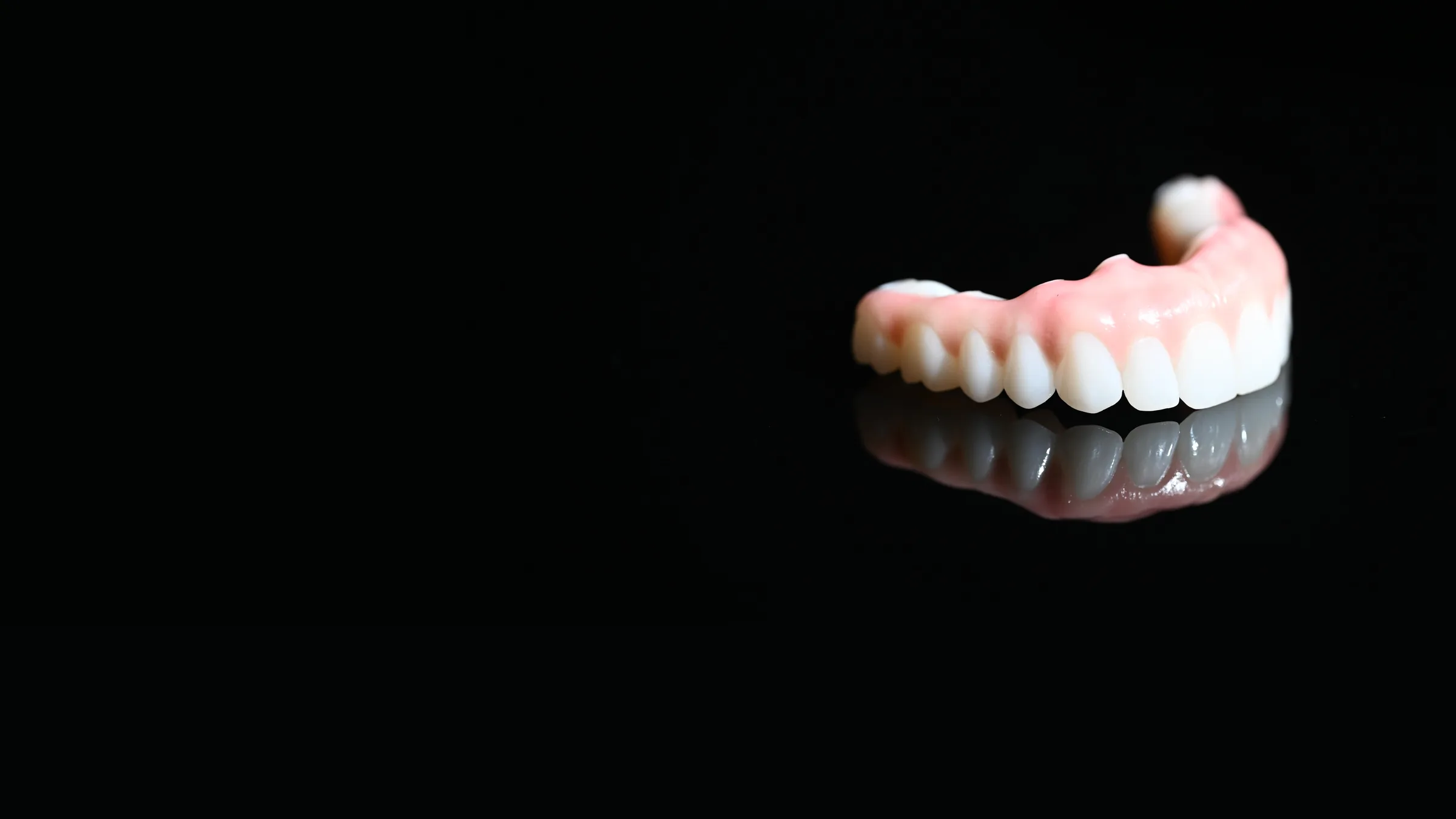 Monolithic zirconia full arch restoration with its reflection on black glass — All-on-X at Smile Spot Dentistry, Venice FL