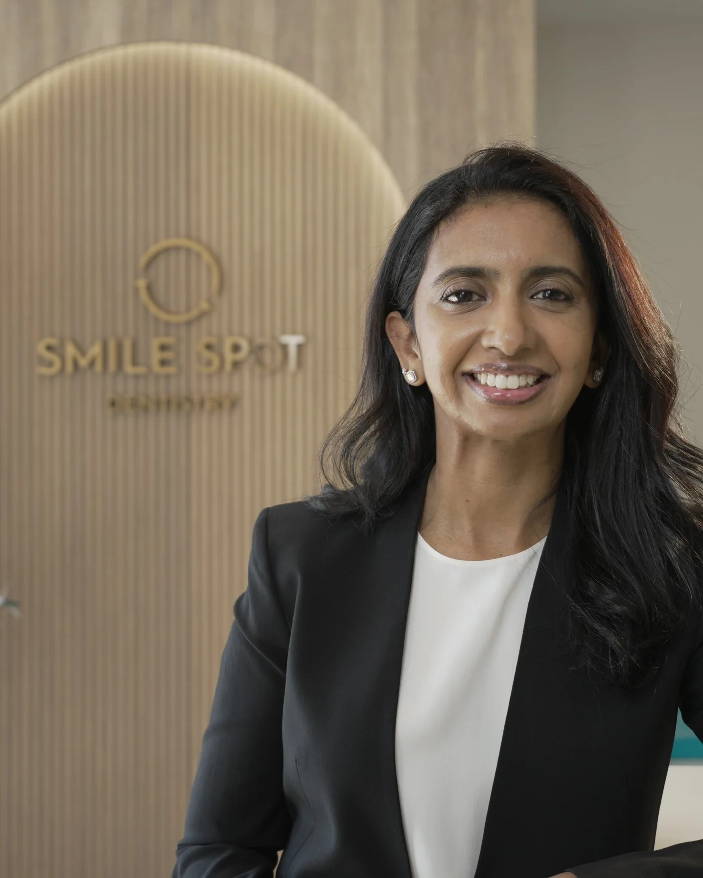 Dr. Meenachi Sellappan, DDS, in front of the Smile Spot logo arch — Smile Spot Dentistry, Venice, FL
