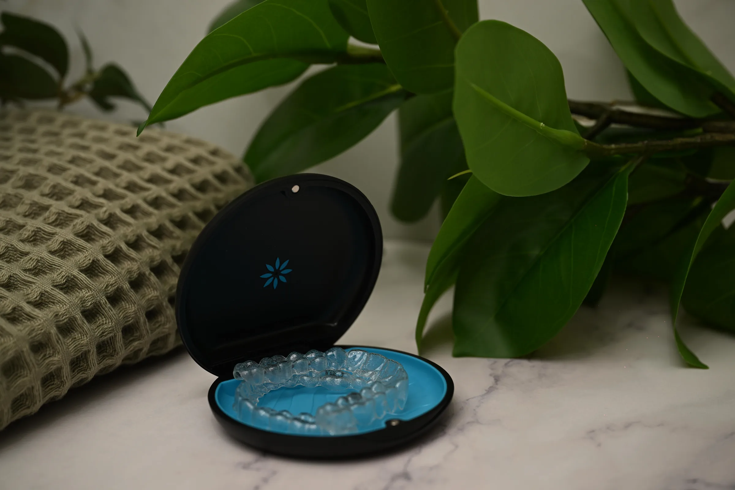 Clear Invisalign aligners in their case on a marble counter