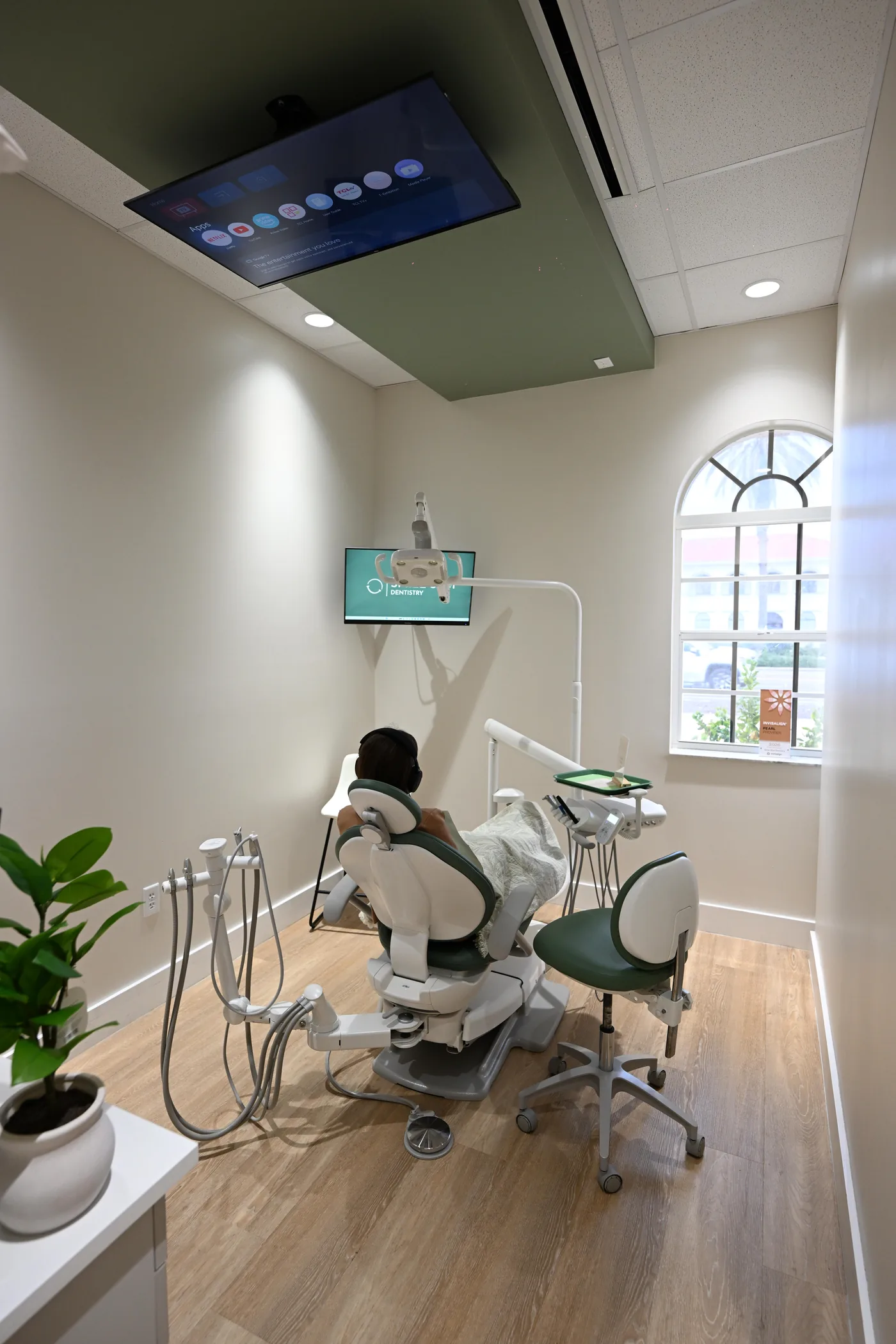 Patient relaxing under a blanket beneath the ceiling-mounted screen in a treatment suite at Smile Spot Dentistry, Venice, Florida